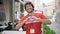 Young hispanic man activist wearing volunteer uniform doing heart gesture at street