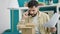 Young hispanic man arguing on smartphone unpacking cardboard box at dinning room