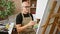 Young hispanic man artist sitting on chair drawing at art studio