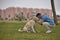 Young Hispanic man, crouching on the grass joining his forehead with his dog\'s forehead in loving and tender attitude.