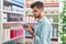 Young hispanic man customer reading label gel hands bottle at pharmacy