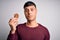 Young hispanic man eating chocolate chips cookie over isolated background with a confident expression on smart face thinking