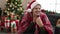 Young hispanic man feeling cold covered with blanket sitting on sofa by christmas tree at home