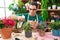 Young hispanic man florist using diffuser watering lavender plant at flower shop