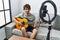 Young hispanic man having online concert playing classical guitar at home