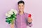 Young hispanic man holding bouquet of flowers and wedding ring smiling with a happy and cool smile on face