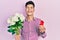 Young hispanic man holding bouquet of flowers and wedding ring smiling and laughing hard out loud because funny crazy joke