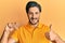 Young hispanic man holding brilliant diamond stone smiling happy and positive, thumb up doing excellent and approval sign