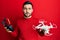 Young hispanic man holding drone and remote control with smartphone relaxed with serious expression on face