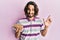 Young hispanic man holding lentils bowl smiling happy pointing with hand and finger to the side