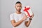 Young hispanic man holding presents relaxed with serious expression on face