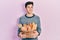 Young hispanic man holding wicker basket with bread smiling looking to the side and staring away thinking