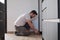 Young hispanic man installing skirting in a new modern kitchen.