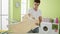 Young hispanic man ironing clothes at laundry room