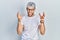 Young hispanic man with modern dyed hair wearing white t shirt and glasses shouting frustrated with rage, hands trying to