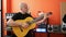 Young hispanic man musician playing classical guitar at music studio