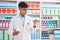 Young hispanic man pharmacist holding pills bottles at pharmacy