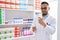 Young hispanic man pharmacist holding pills bottles at pharmacy