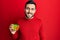 Young hispanic man playing colorful puzzle cube intelligence game looking positive and happy standing and smiling with a confident