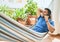 Young hispanic man relaxed talking on the smartphone lying on the hammock at terrace