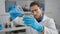 Young hispanic man scientist pouring liquid on glass at laboratory