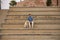 Young Hispanic man, sitting on big cement stairs next to his dog laughing very happy. Concept, dogs, pets, animals, friends