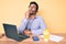 Young hispanic man sitting at the desk wearing operator headset at the call center office serious face thinking about question