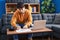 Young hispanic man sitting on sofa teleworking at home