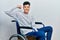 Young hispanic man sitting on wheelchair strong person showing arm muscle, confident and proud of power