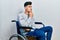 Young hispanic man sitting on wheelchair thinking worried about a question, concerned and nervous with hand on chin