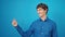 Young hispanic man smiling pointing to the side over isolated blue background