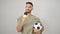 Young hispanic man soccer reporter working using microphone holding football ball over isolated white background