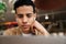 Young hispanic man student sitting at the cafe table indoors