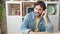 Young hispanic man talking on smartphone sitting on table at dinning room