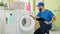 Young hispanic man technician repairing washing machine reading instructions at laundry room