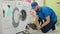 Young hispanic man technician repairing washing machine reading instructions at laundry room