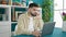 Young hispanic man using laptop with doubt expression at dinning room