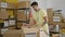 Young hispanic man volunteer packing donations cardboard box at charity center