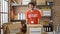 Young hispanic man volunteer smiling confident standing by donations cardboard box at charity center