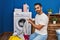 Young hispanic man washing clothes looking t shirt label at laundry room