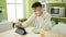 Young hispanic man watching video on touchpad having breakfast at dinning room