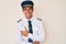 Young hispanic man wearing airplane pilot uniform smiling and laughing hard out loud because funny crazy joke with hands on body