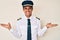 Young hispanic man wearing airplane pilot uniform smiling showing both hands open palms, presenting and advertising comparison and