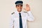 Young hispanic man wearing airplane pilot uniform waiving saying hello happy and smiling, friendly welcome gesture