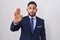 Young hispanic man wearing business suit and tie waiving saying hello happy and smiling, friendly welcome gesture