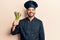 Young hispanic man wearing cooker uniform holding asparagus looking positive and happy standing and smiling with a confident smile