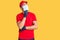 Young hispanic man wearing covid-19 safety mask serious face thinking about question with hand on chin, thoughtful about confusing