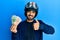 Young hispanic man wearing motorcycle helmet holding south korea won smiling happy and positive, thumb up doing excellent and