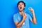 Young hispanic man wearing nurse uniform holding vaccine angry and mad screaming frustrated and furious, shouting with anger