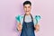 Young hispanic man wearing professional baker apron holding cooking tools celebrating crazy and amazed for success with open eyes